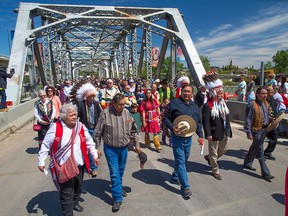 Native elders and flag bearers lead a procession across Reconciliation Bridge during the renaming ceremony for bridge previously known as Langevin Bridge in Calgary on Saturday May 26, 2018.