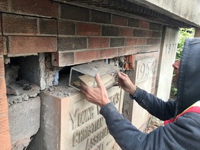 A construction worker pulls one of several time capsule from the cornerstone of the old YWCA building in downtown Calgary on May 31, 2018.