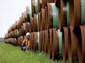 A pipeline worker leans against stockpiled pipe near Hardisty, Alberta.