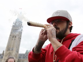(FILES) In this file photo taken on April 20, 2017 A man smokes marijuana on Parliament Hill on 4/20 in Ottawa, Ontario. Canada lawmakers voted to legalize cannabis on June 18, 2018. / AFP PHOTO / Lars HagbergLARS HAGBERG/AFP/Getty Images