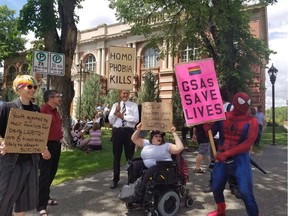 People hold signs outside of a courthouse in Medicine Hat, Alta. on Wednesday, June 20, 2018. A big crowd showed up this morning for the first court challenge to an Alberta law barring schools from telling parents if their children join a gay-straight alliance. A Court of Queen's Bench justice in Medicine Hat is hearing an application from faith-based schools and parents to halt the legislation until there's a ruling on its constitutionality.