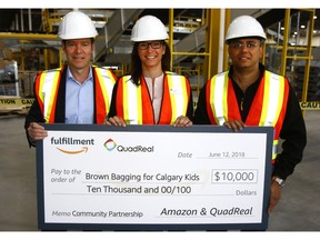 Jeff Hyde, Senior VP Development at QuadReal Property Group, Tanya Koshowski, Executive Director at Brown Bagging For Calgary's Kids and Vibhore Arora, Director of Regional Operations at Amazon hold a cheque for $10,000 that was presented at the new Amazon Fulfillment Centre still under construction in Rockyview County just outside of Calgary. Tuesday, June 12, 2018. Dean Pilling/Postmedia