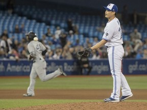 Toronto Blue Jays pitcher Seunghwan Oh takes the ball from his catcher after he gave up a grand slam home run to New York Yankees' Miguel Andujar rounding the bases behind him in the seventh inning of their American League game in Toronto on Tuesday.