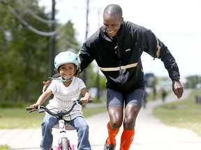 Calgary marathon phenom Bernard Onsare teaches his daughter, Sofia,5, how to ride her new bike with his winnings from last weekends marathon win at Edworthy Park in Calgary on Wednesday June 13, 2018. Darren Makowichuk/Postmedia