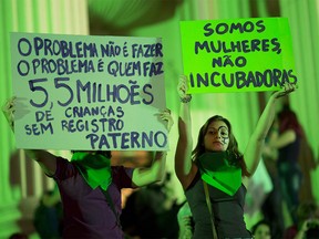 A demonstrator, right, holds a sign with a message that reads in Portuguese: "We are women, not incubators", as she joins others  in a protest demanding the legalization of abortion without exception, in Rio de Janeiro, Brazil, Friday, June 22, 2018. Abortion is illegal in Brazil, except when a woman's life is at risk, when she has been raped or when the fetus has a usually fatal brain abnormality called anencephaly. (AP Photo/Silvia Izquierdo) ORG XMIT: XSI123