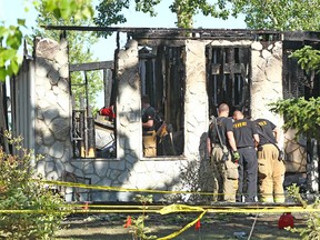 Firefighters look through a burned out house on Lake Ere Estate in Chestermere, east of Calgary after an early morning fire on Tuesday, June 12, 2018. The Chestermere RCMP confirm that they are investigating the death of an adult male who was located on the property. The death is preliminary, it is not considered suspicious. Jim Wells/Postmedia