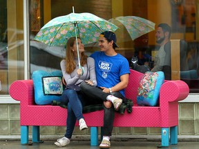 A couple waits under an umbrella outside of Red's Diner on 4th Street S.W. near downtown Calgary on June 22, 2018. After a few days of hot weather, thundershowers have moved into the area.
