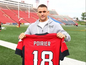 UFC fighter Dustin Poirier poses with a Calgary Stampeders jersey following practice at McMahon Stadium in Calgary on May 30, 2018.