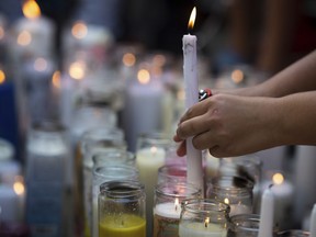 In this Tuesday, June 19, 2018 photo, fans and community members light candles as they gather at a vigil for rap singer XXXTentacion in Deerfield Beach, Fla., near the site where the troubled rapper-singer was killed the day before. The 20-year-old rising star, whose real name is Jahseh Dwayne Onfroy, was shot outside the motorcycle dealership on Monday, June 18, when two armed suspects approached him, authorities said.