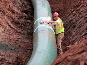 In this Aug. 21, 2017, file photo, a pipe fitter lays the finishing touches to the replacement of Enbridge Energy's Line 3 crude oil pipeline stretch in Superior, Minn.