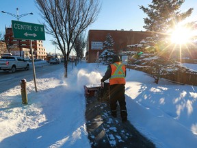 Workers clear sidewalks along 16th Avenue N.W. on Feb. 5, 2018.