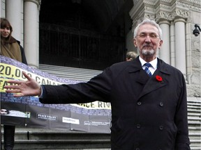 MLA Leonard Krog, (left), looks on as Sierra Club B.C. Galen Armstrong gathers petitions, postcards and messages of solidarity from inside a canoe following the government's reports on the controversial Site C dam study during a protest on Lekwungen Territory at Legislature in Victoria, B.C., on Thursday, November 2, 2017.