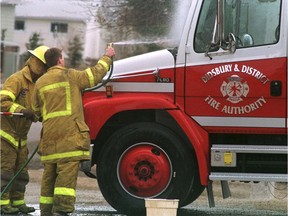 Didsbury volunteer firefighters Lee Penner (hose) and Pierre Martel clean up a fire truck.