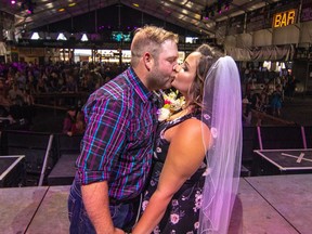 Geoff Gorzitza and Brittany Orsulak celebrate with a kiss after they tied the knot at the Cowboys Shotgun Wedding in the big Cowboys tent at the Calgary Stampede in Calgary, Ab., on Saturday July 14, 2018. Mike Drew/Postmedia