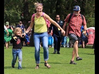 Heather Wacker skips with her son Finn, 4, across the grass to set up their tarp at the start of the Calgary Folk Festival on Prince's Island on Thursday July 26, 2018.