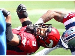 Calgary Stampeders running back Jon Cornish takes a nasty hit from Montreal Alouettes, Kyries Hebert in second-half action during the home opener at McMahon Stadium in Calgary on Saturday June 28, 2014. File photo by Darren Makowichuk/Postmedia.