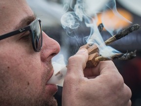 A man smokes three joints at once while attending a marijuana celebration, in Vancouver, B.C., on April 20, 2018.