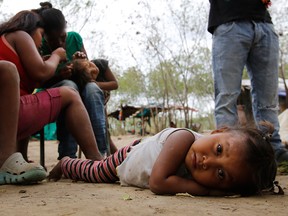A Venezuelan indigenous Yupka girl plays on the ground while another gets lice picked from her head at a camp set up in Cucuta, Colombia, near the border with Venezuela. Along the banks of the Tachira River dividing Colombia and Venezuela, many of the indigenous children have lice and distended bellies from malnutrition or parasites. Tribe leader Dionisio Finol said they are better off there than in Venezuela, where at least they can eat. (AP Photo/Fernando Vergara)