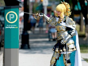 Natalie Matria, who is dressed as Elli from Lovelive has a mock battle with a parking pay machine in Kensington during the Fantasy Faire in Calgary Sunday, July 29, 2018. Jim Wells/Postmedia