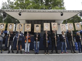 Demonstrators hold signs with people killed by the NSU outside the court in Munich, southern Germany, prior to the verdict Wednesday, July 11, 2018.