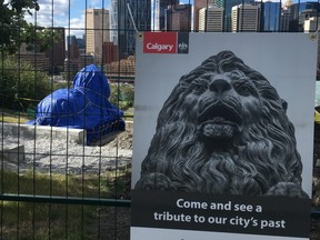 One of the original lion statues from the Centre Street bridge sits beneath a tarp overlooking the city at Rotary Park. Gavin Young/Postmedia