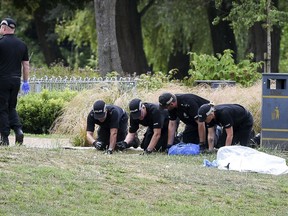 Police conduct fingertip searches of Queen Elizabeth Gardens, in Salisbury, which British woman Dawn Sturgess visited before she fell ill after being exposed to nerve agent Novichok, Thursday, July 19, 2018. Senior coroner David Ridley opened an inquest into the poisoning death of Sturgess Thursday, but said the cause of Sturgess' death won't be given until further tests are completed.