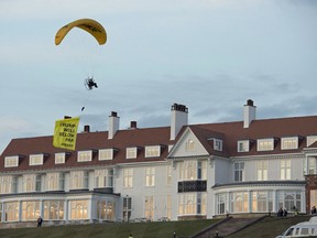 In this Friday, July 13, 2018 photo, a Greenpeace protester flying a microlight passes over Donald Trump's resort in Turnberry, South Ayrshire, Scotland with a banner reading 'Trump: Well Below Par.'