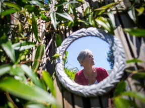 Marilyn Lenzen is reflected in a mirror on the fence in the backyard of her home as she poses for a photograph, in North Vancouver, B.C., on Monday July 16, 2018. The largest-ever study to document symptoms of multiple sclerosis suggests patients had higher rates of certain conditions five years before they developed the first clinically recognizable signs of the disease. Researchers from the University of British Columbia say sleep problems, fibromyalgia, irritable bowel syndrome, migraine headaches, depression and bipolar disorder were more common among patients who were later diagnosed with MS, based on examination of health records in four provinces between 1984 and 2014.