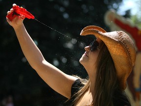 Calgary's Jill Kowalchuk used a squirt gun as she tried to beat the heat at the Calgary Stampede grounds  on Saturday as temperatures soared into the 30's. Credit: Colleen De Neve / Calgary Herald