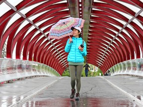 Yanna Liu, visiting from the United States, didn't let the rain prevent her from exploring the city including the Peace Bridge over the Bow River in Calgary on Monday July 2, 2018.  Gavin Young/Postmedia