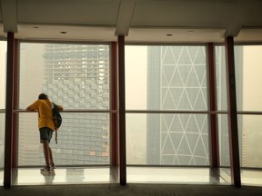 A young boy looks at a smokey downtown skyline from the observation deck at the Calgary Tower on Wednesday August 15, 2018. Leah Hennel/Postmedia