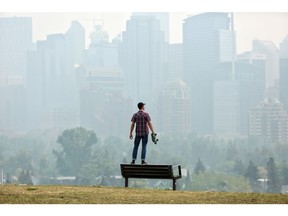 Andres Saez takes a look at a smoke filled downtown in Calgary earlier this week. Leah Hennel/Postmedia