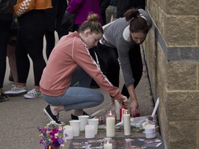Hannah Carly, left, and her mother Carly Beharry, place a candle at a vigil for the Metko family on August 4th, 2018. The father, 45-year-old Fetko, and his 14-year-old son Fioralb, died in an Ontario crash last Sunday night while the man's wife and daughter were hospitalized.  (Zach Laing / Postmedia Network)