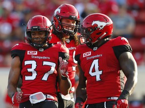 Calgary Stampeders Maleki Harris, Alex Singleton and Micah Johnson celebrate after brings down Trevor Harris of the Ottawa Redblacks during CFL football in Calgary. AL CHAREST/POSTMEDIA