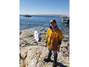 Albert Netser tweeted this picture of his 16-year-old son Nangaat standing on a rock in Rankin Inlet, Nunavut with his first harvested beluga whale on Monday in this handout photo. Netser says he didn't expect to be at the brunt of controversy.