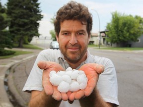 Kemal Ciftci, who was working on a house on Canterbury Place SW, holds up hailstones in the Canyon Meadows neighborhood in Calgary on Thursday, August 2, 2018. Yet another violent storm rolled through the city, pelting neighborhoods with heavy rain and hail. Jim Wells/Postmedia