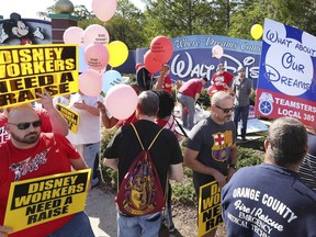 FILE- In this March 23, 2018, file photo, unionized workers for Walt Disney World and their supporters march and chant in front of Disney hotel property in Orlando, Fla. Disney’s unionized workers will vote in early September on the proposal to raise the starting minimum wage from $10 to $15 an hour by 2021.