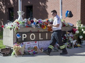 Paramedic Brian Fournier walks away after playing a hymn and placing a tribute at the police station in Fredericton on Friday, Aug. 10, 2018. Thousands of police officers and other first responders from across North America are in Fredericton today for the funeral of two police officers who were gunned down last week with two civilians in the parking lot of a city apartment complex.