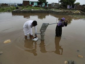 Indians collect drinking water from a hand pump at a flooded street following monsoon rains in Jammu, India, Monday, Aug.13, 2018. India's monsoon season runs from June to September.