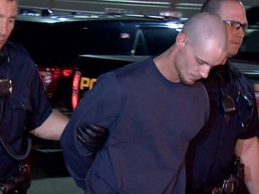 Officers lead suspect Dustin Duthie into the Calgary Police Service arrest processing unit. Photo courtesy of CBC Calgary