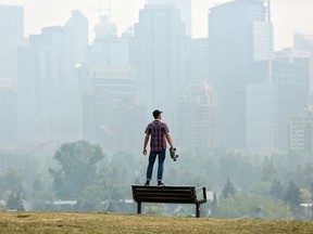 Andres Saez surveys a smoke-filled downtown in Calgary on Thursday, Aug. 16, 2018.