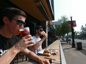 Hayden Cameron (L and Owen Goerzen enjoy a prime spot and a cold beverage at Trolley 5 on 17 Ave SW duirng the lunch hour in Calgary Friday, August 10, 2018. Jim Wells/Postmedia