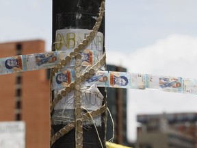 FILE - In this July 20, 2017 file photo, devalued Bolivar bank notes and coins, taped together, serve as makeshift rope at a roadblock set up by anti-government protesters in Caracas, Venezuela. The Venezuelan government presented to the Constitutional Assembly on Thursday, August 2, 2018, a decree that would make all operations at foreign exchange houses legal again.