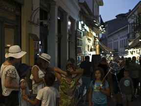 In this Friday, Aug. 17, 2018 photo, tourists walk in Plaka neighborhood of Athens. The one area of the economy that's flourishing is tourism, with officials projecting a record-high 32 million arrivals this year. Greeks, however, are finding it increasingly expensive to go on holiday in their own country, while a boom in short-term rentals in residential districts of Athens has driven rents beyond the reach of many locals.