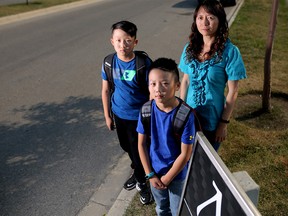 Cindy Lui is upset at the early time her boys Ethan Tang, 11, left, and Evan Tang, 9 have to catch their bus. They are pictured at the bus stop in Auburn Bay in south Calgary.