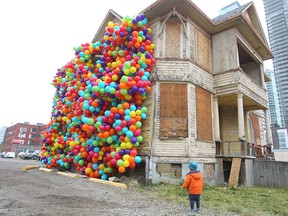 Jake England checks out a Beakerhead installation called Dreams Never Die on 11th Avenue S.E. on  Wednesday, Sept. 19, 2018. The installation, designed by artist Maria Galura, is inspired by the Pixar movie Up and is made up of hundreds of weather-resistant, bio-degradable balloons wrapping part of a house in Victoria park.
