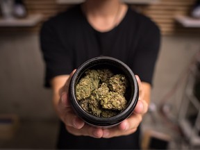 An employee displays marijuana for sale at the Village Bloomery dispensary in Vancouver, on Monday, Sept. 17, 2018.