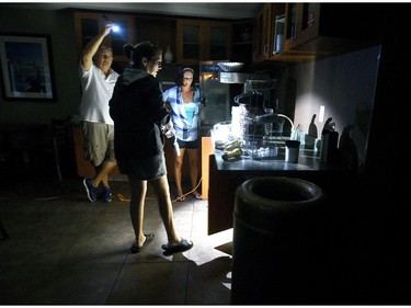 CORRECTS DAY OF THE WEEK TO FRIDAY INSTEAD OF THURSDAY - Mitchell Floor, left, holds a flashlight as Comfort Suites general manager Beth Bratz, center, and employee Dee Branch go to make coffee as Hurricane Florence rages in Wilmington, N.C. Friday, Sept. 14, 2018. The area lost power around 4 a.m. and the facility was running small lights, phone chargers and the coffee machine on a generator. (Chuck Liddy/The News & Observer via AP) ORG XMIT: NCRAL601