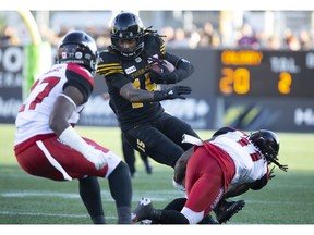 Hamilton Tiger-Cats wide receiver Alex Green (15) tries to get past Calgary Stampeders defensive back Tunde Adeleke (27) and defensive back Troy Stoudermire (11) during second half CFL Football game action in Hamilton, Ontario on Saturday, September 15, 2018.