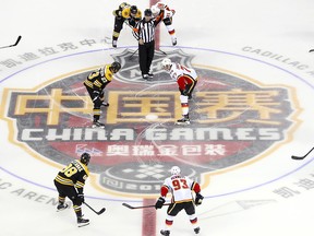 Jakob Forsbacka Karlsson (23) of the Boston Bruins, centre left, and Mark Jankowski (77) of the Calgary Flames face off at the start of their 2018 NHL China Games hockey game in Beijing, China, Wednesday, Sept. 19, 2018. (AP Photo/Mark Schiefelbein)